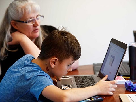 Caidence Miller, a 4th grader, tries to figure out assignment instructions on his laptop as his grandmother watches him navigate the online learning system the Northshore School District will use for two weeks due to coronavirus concerns, in Woodinville, Washington, US on March 11, 2020.
