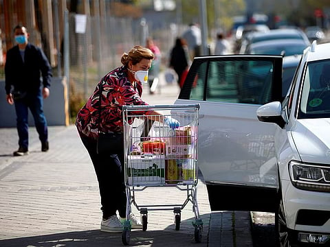 A woman wearing a protective mask loads her shopping in a car, amidst concerns over Spain's coronavirus outbreak in central Madrid, Spain, March 14, 2020.