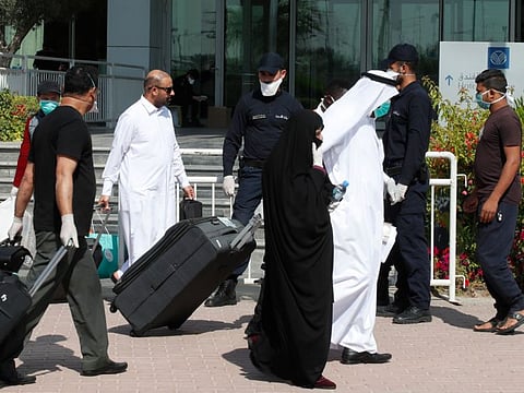 Qatari police stand outside a hotel in Doha as a medical worker walks alongside people wearing protective masks over fears of coronavirus on March 12. Most of Qatar's 337 infections can be traced back to Iran.