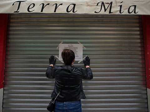 A woman hangs a sign announcing that her bar will remain closed in central Malaga, Spain on March 15.