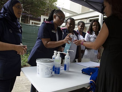 A woman, right, sanitises her hands while undergoing screening at an entrance to the Milpark Hospital in Johannesburg on March 11.