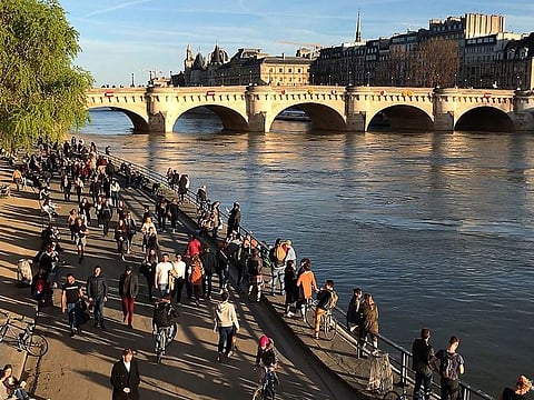 People walk on the banks of the river Seine in Paris on March 15, 2020, as cafes and restaurants are closed amid the COVID-19 outbreak.