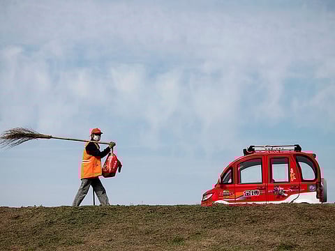 A street cleaner wearing a face masks walks along a street in Jiujiang, in China’s central Jiangxi province that borders Hubei province, the epicentre of the country's COVID-19 coronavirus outbreak, on March 15, 2020.