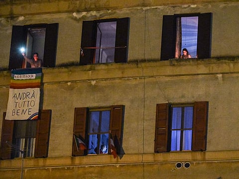 People hold lights, candles, flashlights or smartphones's light, from windows or balconies, during a flash mob " Italia Patria Nostra" (Italy Our Country) at the Garbatella district in Rome on March 15, 2020.
