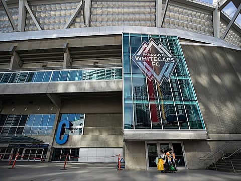 A worker cleans windows and doors at B.C. Place stadium, where Major League Soccer's Vancouver Whitecaps play their home games, in Vancouver, British Columbia, Thursday, March 12, 2020.
