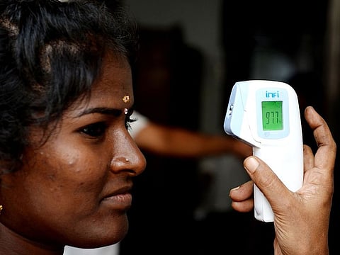 A health worker checks the body temperature of a worker amid concerns over the spread of the COVID-19 novel coronavirus in Chennai on March 16, 2020.