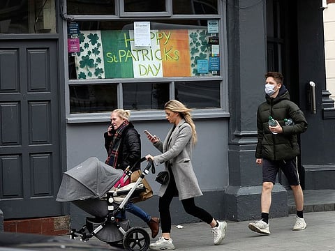 A man wearing a face mask walks past a closed pub in Dublin city centre