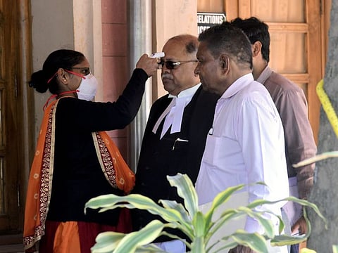 Security staff uses a thermal screening device on visitors at the entry gate, at the Supreme Court of India in New Delhi on Monday.