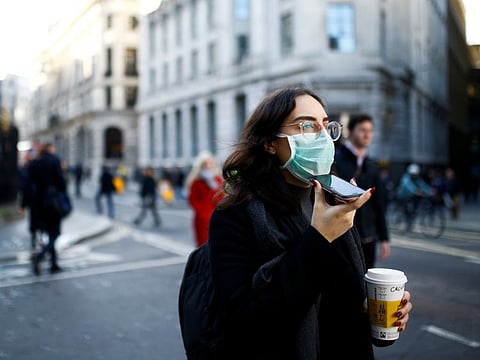 People, some wearing protective face masks, walk through the City of London, as the number of coronavirus cases worldwide continues to grow, in London on March 16, 2020.