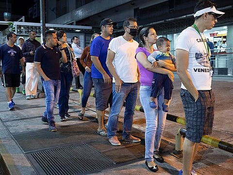 People line up outside a supermarket after President Nicolás Maduro ordered residents in the capital of Caracas and six states to stay home under a quarantine in a bid to control the spread of the coronavirus in Caracas, Venezuela, Sunday, March 15, 2020.