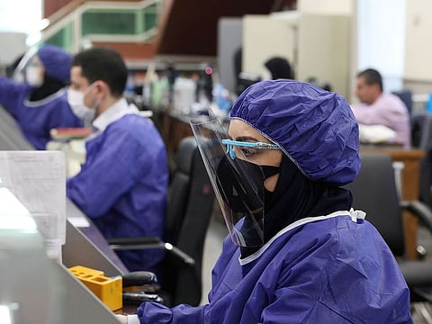 Bank employees wear protective face masks and clothes during the work in Tehran.