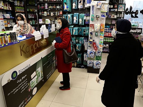 Customers wait as a pharmacist prepares medicines, in Tehran, Iran.