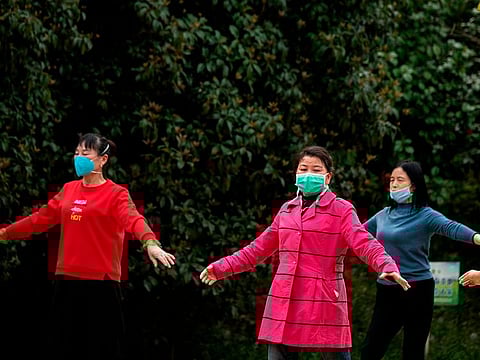 Women wearing face masks dance at a park in Jiujiang, a city which sits on the border between China’s central Jiangxi province and Hubei province, the epicentre of the country's COVID-19 coronavirus outbreak, on March 17, 2020.