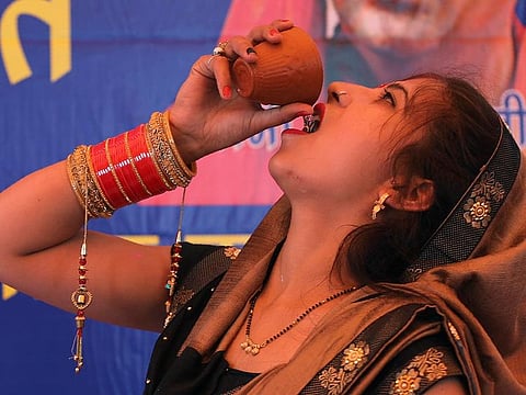 An Indian Hindu woman drinks cow urine during an event organized by a Hindu religious group to promote consumption of cow urine as a cure for the new coronavirus in New Delhi, India, Saturday, March 14, 2020.