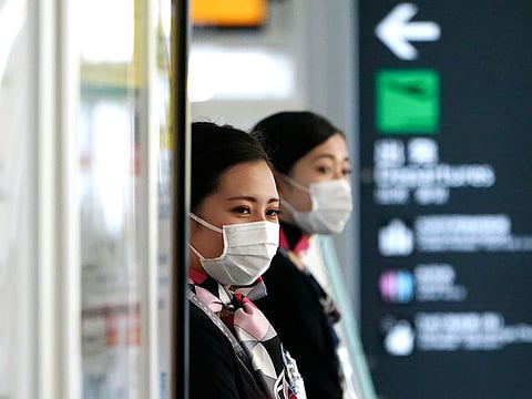 Airlines ground crews with protective masks to protect against the coronavirus stand at a check-in counter at the Haneda International Airport in Tokyo.