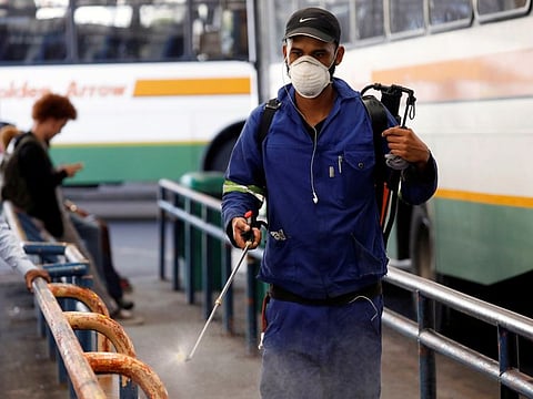 A health worker sprays disinfectant on railings to combat the spread of coronavirus disease (COVID-19) at a bus depot in Cape Town, South Africa, March 18, 2020.