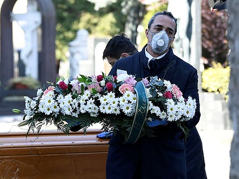 Cemetery workers and funeral agency workers in protective masks transport a coffin of a person who died from coronavirus disease (COVID-19), into a cemetery in Bergamo, Italy.