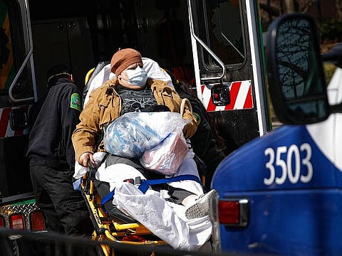 A patient wears a protective face mask as she is loaded into an ambulance at The Brooklyn Hospital Center emergency room in New York.