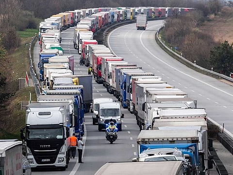 A German police officer drives a motorcycle between trucks, which jam the motorway A4 near Goerlitz, Germany, on Thursday, March 19, 2020. Thousands of truck drivers have to hold out in a traffic jam, which has grown to a length of about 40 kilometers, before the border with Poland.