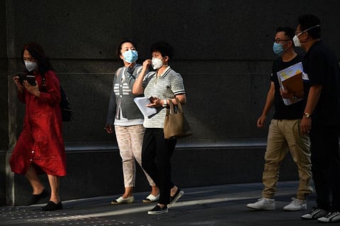 People wearing face masks, amid concerns of the COVID-19 coranavirus, walk on a street in Sydney on March 19, 2020.