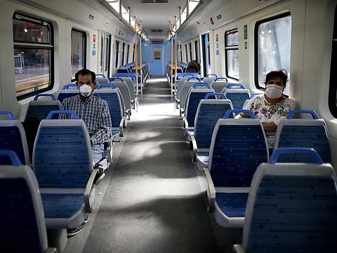 People wearing masks, as a precaution against the spread of the new coronavirus, ride an empty train in Buenos Aires, Argentina, Friday, March 20, 2020. Argentine's government has ordered residents to quarantine themselves until the end of the month to help contain the spread of COVID-19. Argentina's proposal for a three-year debt payment moratorium and steep cuts in interest rates could be taken as an example in future sovereign restructuring, UN said.