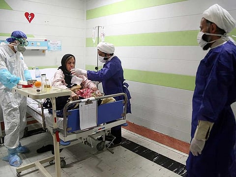 In this Saturday, March 7, 2020 file photo, a cleric, right, assists a medic treating a patient infected with the new coronavirus, at a hospital in Qom, about 80 miles (125 kilometers) south of the capital Tehran, Iran.