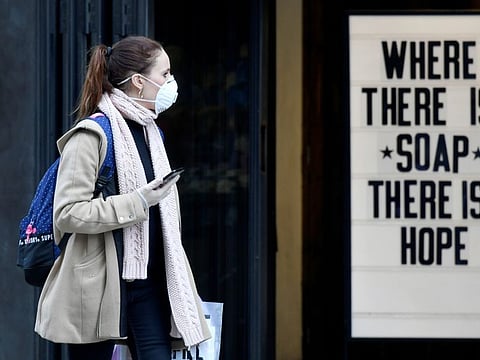 A woman wearing a protective face mask walks past a shop, as the spread of the coronavirus disease (COVID-19) continues, in London on March 20, 2020.