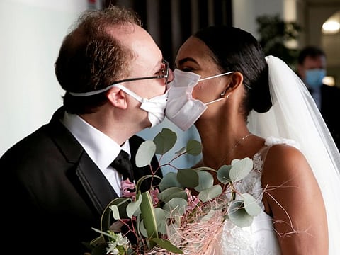 Newlyweds Diego Fernandes, 46 and Deni Salgado, 30, kiss through protective face masks at a wedding ceremony with only witnesses and no guests, as public gatherings are banned as part of Italy's lockdown measures to prevent the spread of coronavirus disease (COVID-19) in Naples, Italy, March 20, 2020. REUTERS/Ciro De Luca TPX IMAGES OF THE DAY