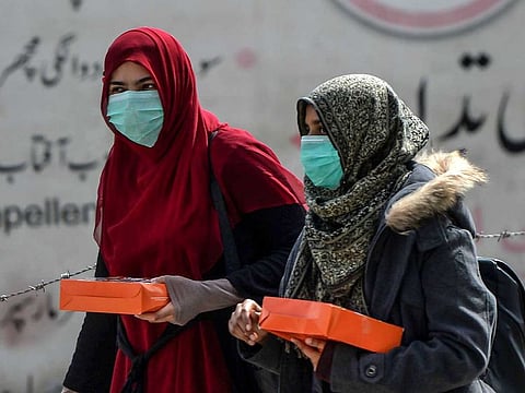 Women wearing facemasks as a preventive measure against the spread of the COVID-19 coronavirus walk along a street in Rawalpindi on March 13, 2020.