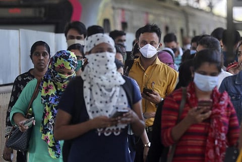 Commuters wearing protective face masks walk at a metro station in Mumbai on Thursday, March 19, 2020.