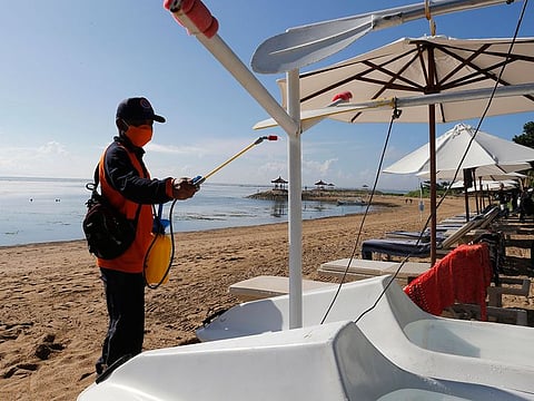 An official sprays disinfectant to prevent the new coronavirus at a beach in Bali, Indonesia on Sunday, March 15, 2020.