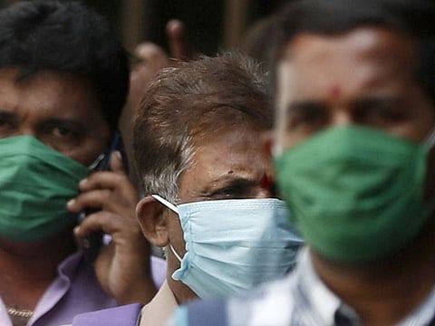 Men wearing protective masks walk inside the premises of a hospital where a special ward has been set up for the coronavirus disease in Mumbai.