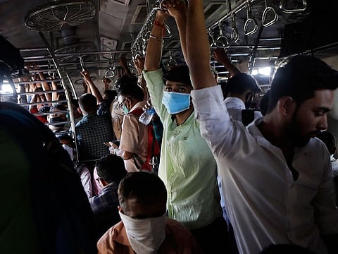 Indian commuters, some wearing protective masks as a precaution against COVID-19 travel in a crowded local train in Mumbai, India, Friday, March 20, 2020.