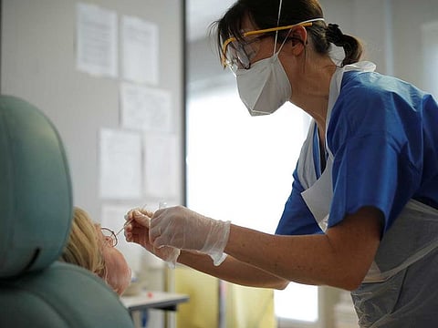 A medical worker performs a test on a woman suspected to be infected at the hospital in Vannes, France, where patients suffering from coronavirus disease are treated, on March 20, 2020.