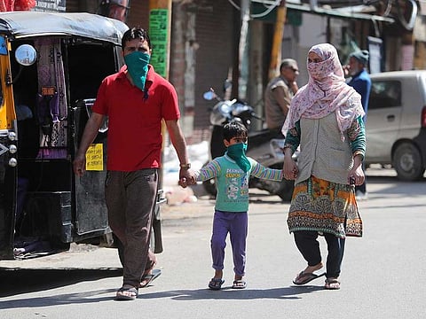 A family with their faces covered as a precaution against COVID-19 walk through a closed market during restrictions in Jammu, India, on March 20, 2020.