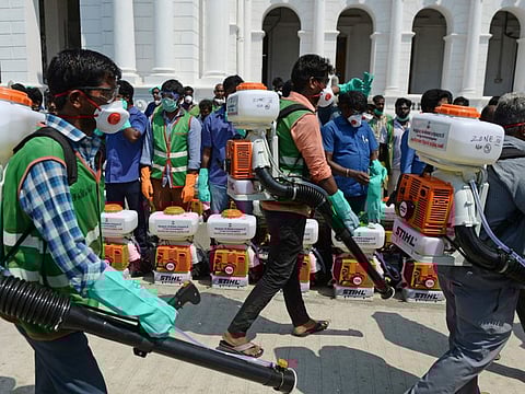 Health workers wearing facemasks amid concerns over the spread of the COVID-19 novel coronavirus, prepare to spray disinfectant at the corporation office in Chennai on March 20.