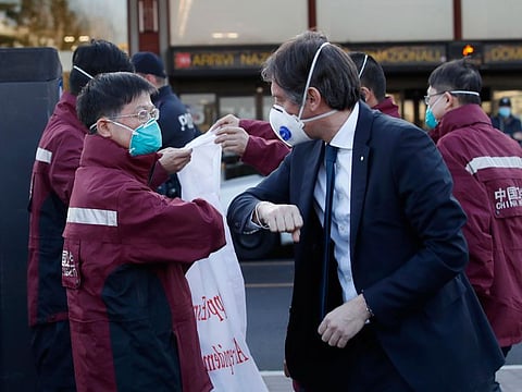 Vice President of Region Lombardy Fabrizio Sala, right, salutes with his forearm medics and paramedics from China upon arrival at the Malpensa airport of Milan, Wednesday, March 18, 2020. Some 37 between doctors and paramedics were sent along with some 20 tons of equipment, and will be deployed to different hospitals in Italy's most affected area.