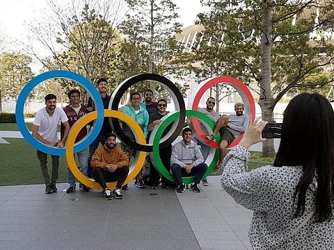 A group of students from Uruguay pose for a souvenir picture on the Olympic Rings set outside the Olympic Stadium in Tokyo, Saturday, March 21, 2020.
