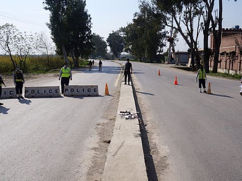 Police officers stand guard at a blocked road leading to Manga village after an outbreak of coronavirus disease (COVID-19), in Marden, Pakistan March 19, 2020. Picture taken March 19, 2020. REUTERS/Abdul Sattar NO RESALES. NO ARCHIVE.