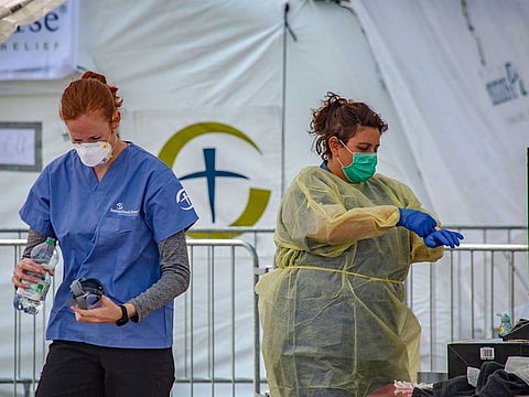 Medical workers sanitise themselves at a field hospital to be run by non-governmental organisation, Samaritan's Purse, outside Cremona hospital, in Cremona, Italy, on Sunday, March 22, 2020.