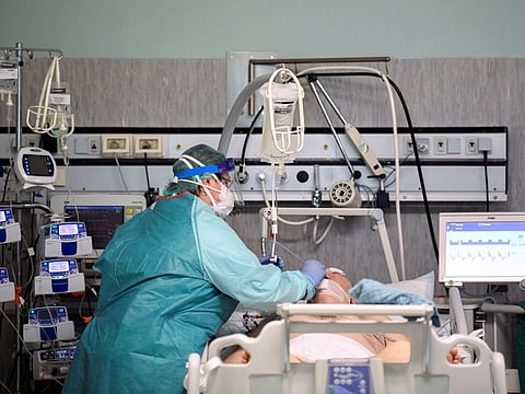 A medical worker wearing a protective mask and suit treats a patient suffering from coronavirus disease (COVID-19) in an intensive care unit at the Oglio Po hospital in Cremona, Italy.