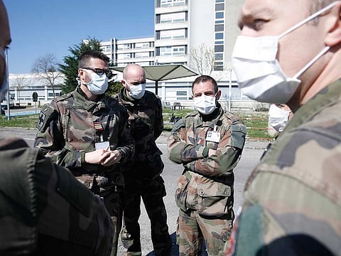 Military doctors talk by the military field hospital in Mulhouse, eastern France, Tuesday, March 24, 2020. The Grand Est region is now the epicenter of the outbreak in France, which has buried the third most virus victims in Europe, after Italy and Spain. For most people, the new coronavirus causes only mild or moderate symptoms. For some it can cause more severe illness.