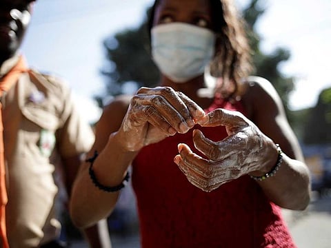 A woman wearing a protective mask washes her hands at a hand-washing station set up by Haitian Boy and Girl Scouts to prevent the spread of coronavirus disease (COVID-19) in Port-au-Prince, Haiti.