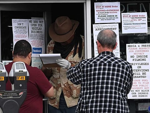 People wait to check in for their appointment to enter Martin B. Retting gun shop in Culver City, California on March 24, 2020. Due to the statewide stay-at-home order from California Governor Gavin Newsom Martin B. Retting is only accepting appointments with buyers who have already placed orders. Gun stores have seen an uptick in business as a result of the spreading coronavirus pandemic.