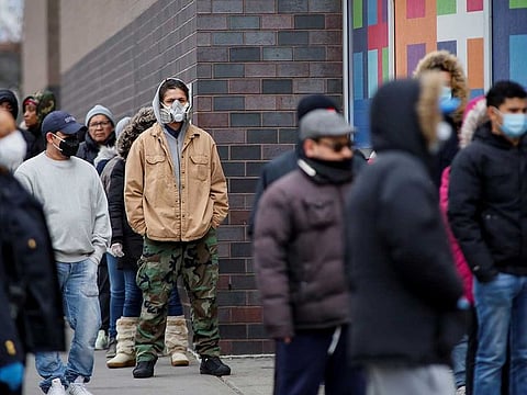 People wait in line to be tested for coronavirus disease while wearing protective gear.