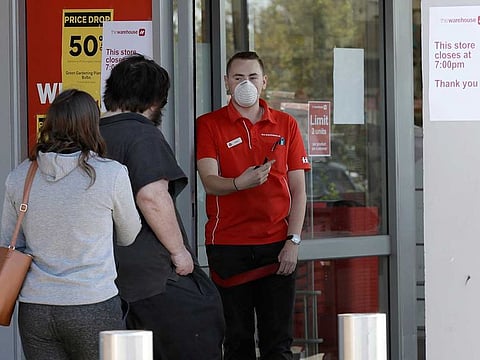 A store staff member allows customers to enter a department store in Christchurch, New Zealand, on Wednesday, March 25, 2020. New Zealand will close schools and non-essential services at midnight on Wednesday as the country goes into lockdown to try to stop the spread of coronavirus pandemic.