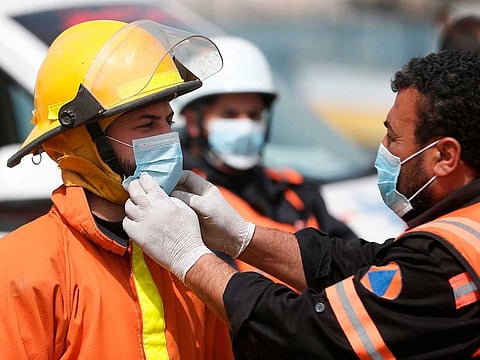 Members of the Palestinian civil defence force wear protective masks before spraying disinfectant in the port area of Gaza City on March 24, 2020 to contain the novel coronavirus outbreak.