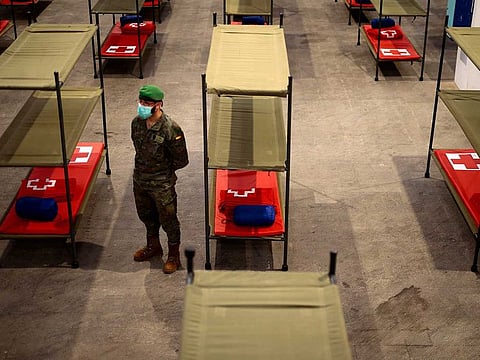 A Spanish soldier stands next to beds set up at a temporary hospital for vulnerable people at the Fira Barcelona Montjuic centre in Barcelona on March 25, 2020, during the new coronavirus epidemic.