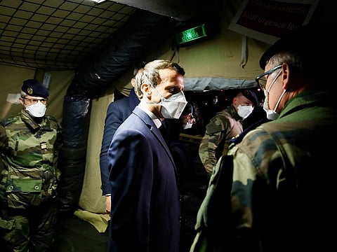 French President Emmanuel Macron, centre, wears a face mask as he visits the military field hospital in Mulhouse, eastern France, Wednesday, March 25, 2020.