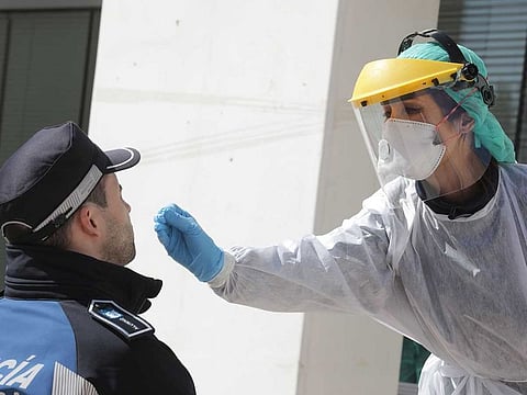 A health worker uses a swab to test a municipal police officer for the COVID-19 coronavirus in Madrid on March 25, 2020.